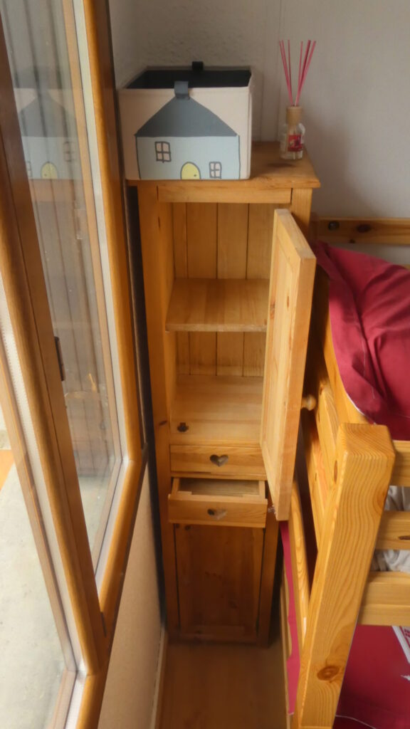 Rangements en bois derrière un des lits superposés de la chambre
